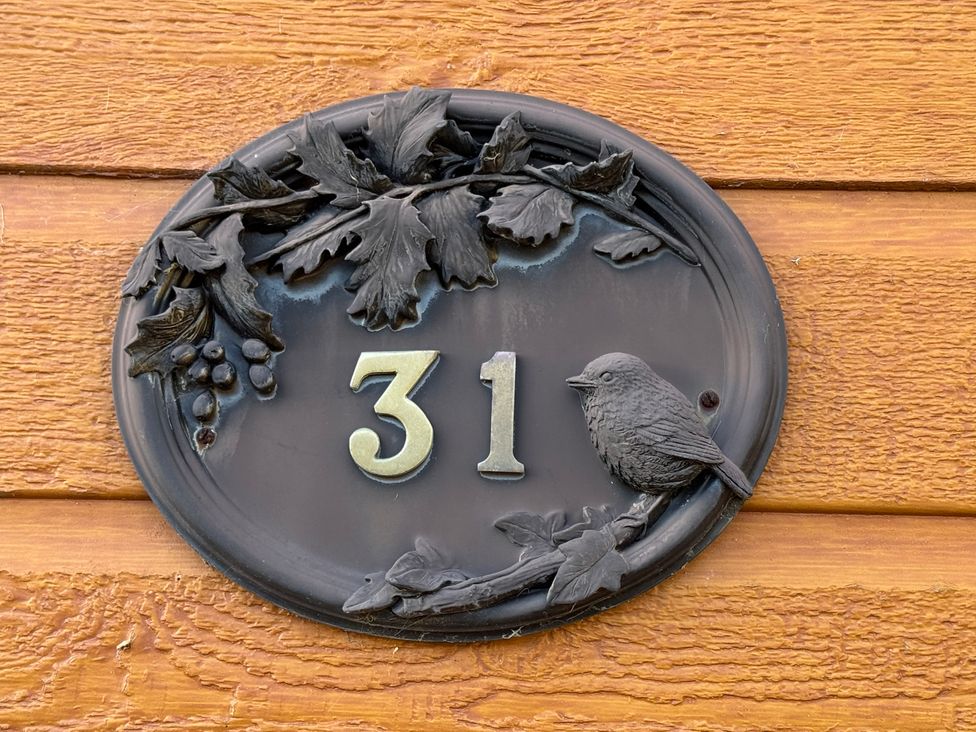 A house number plaque with a bird and leaves at Woodland View 31 - The Hawthorns Finlakes Holiday Park near Chudleigh