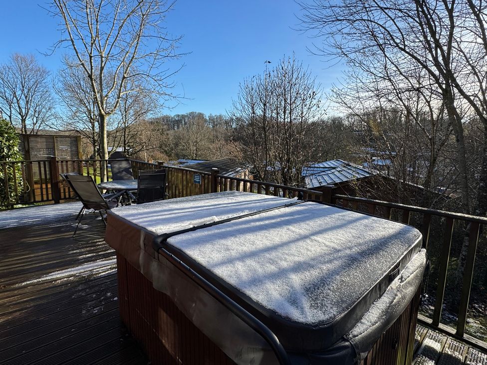 A deck with a hot tub and chairs at Woodland View 31 - The Hawthorns Finlakes Holiday Park near Chudleigh