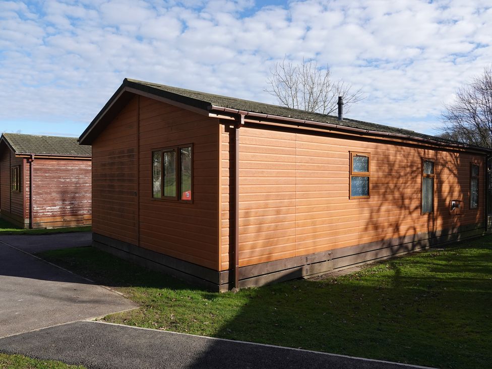A wooden lodge with windows and a door at Woodland View 31 - The Hawthorns near Finlakes Holiday Park