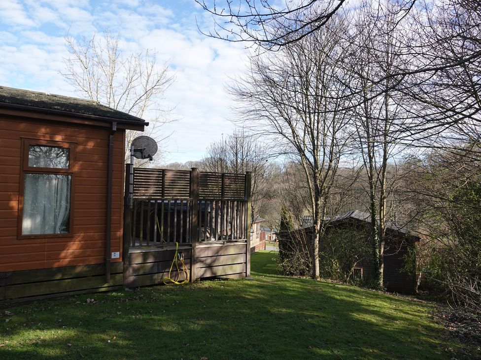 A wooden lodge with a satellite dish and decking at Woodland View 31 - The Hawthorns near Finlakes Holiday Park near Chudleigh