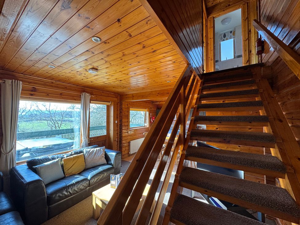 A living room with a sofa and stairs at Tor View in Finlakes Holiday Park near Chudleigh