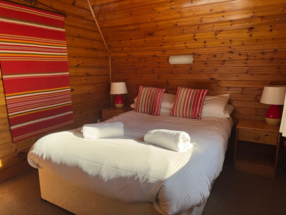 A bedroom with a bed, side tables and lamps at Tor View, Finlakes Holiday Park near Chudleigh