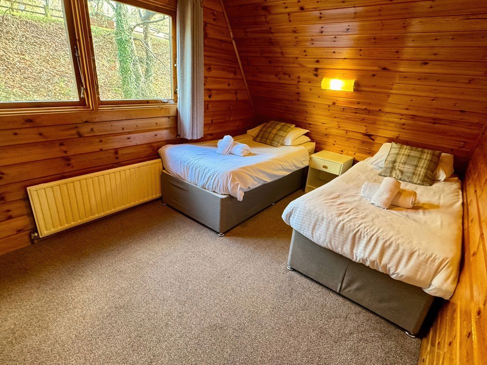 A bedroom with two beds and a bedside table at Tor View Finlakes Holiday Park near Chudleigh