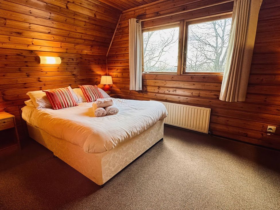 A bedroom with a bed and windows at Tor View Finlakes Holiday Park near Chudleigh