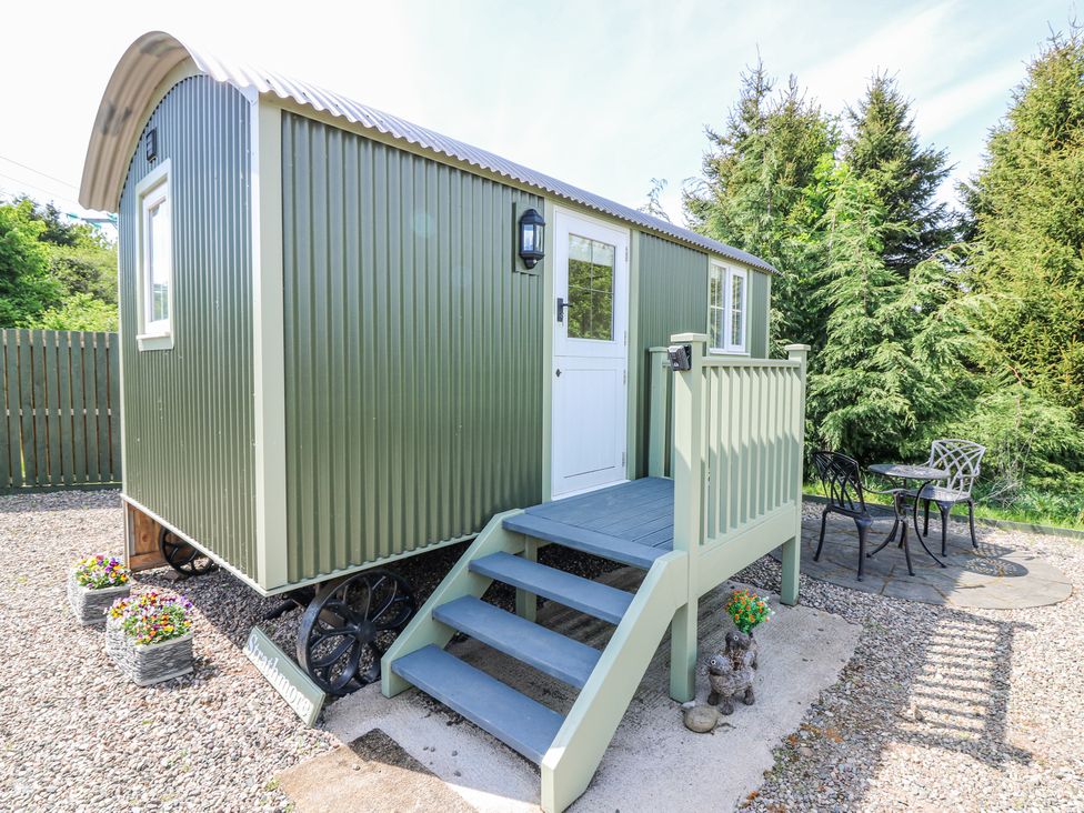 A small green cabin on wheels with stairs leading to a white door and outdoor seating at Airlie Burnside near Forfar