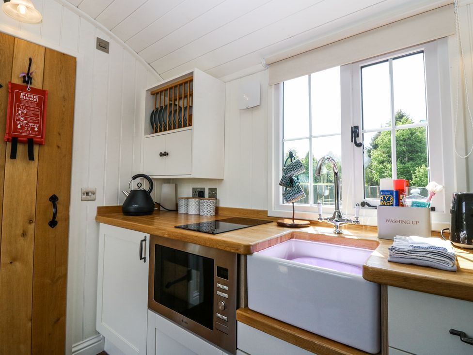 A kitchen with wooden countertops a white sink microwave kettle and window at Airlie Burnside near Forfar
