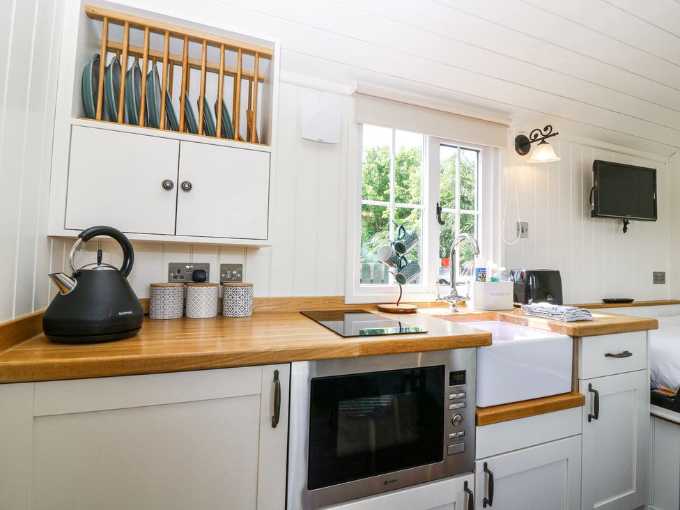 A kitchen with a wooden countertop and white cabinets a window above the sink at Airlie Burnside near Forfar