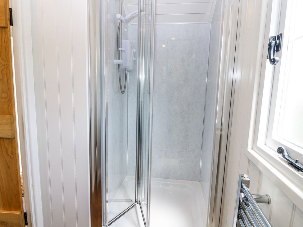 A small bathroom with a corner shower enclosure a shower unit and a window at Airlie in Burnside near Forfar