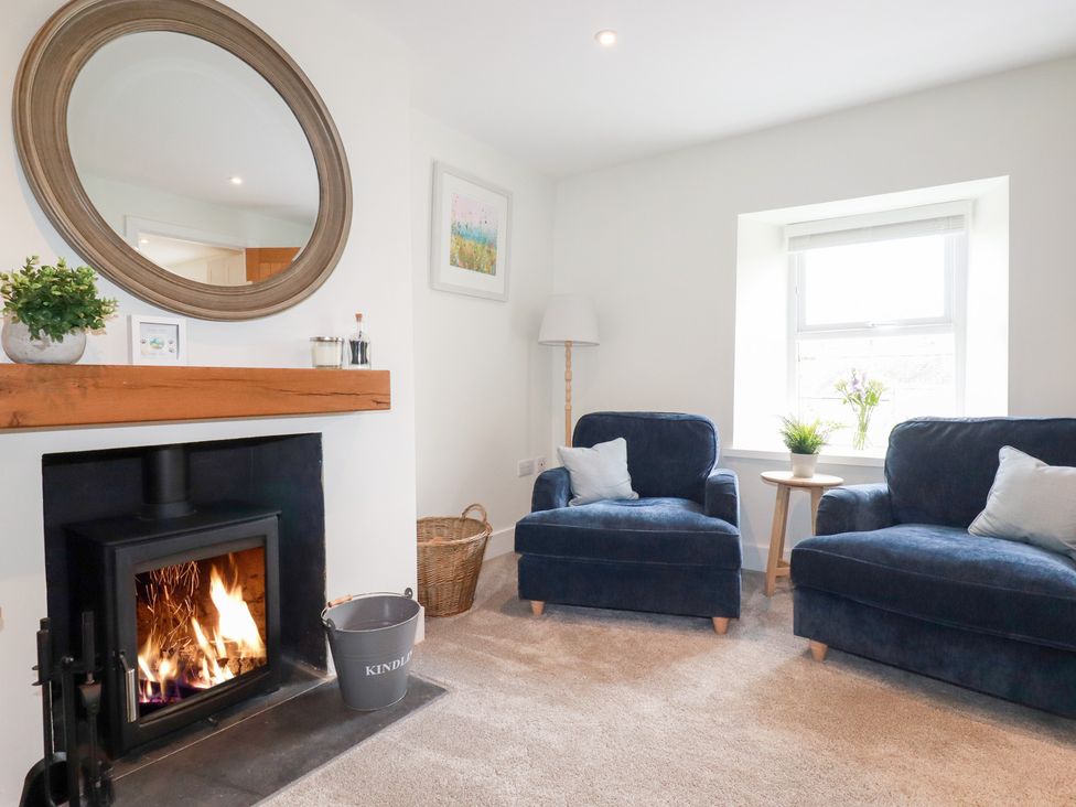 A living room with a fireplace and armchairs at Glendale in Port Isaac