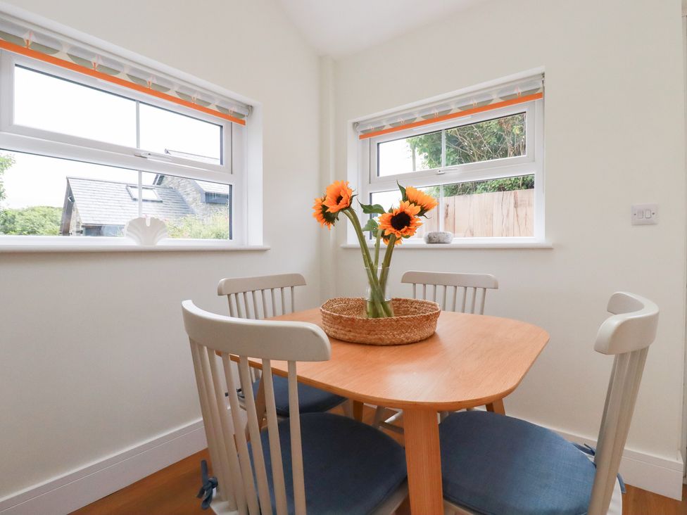 A dining room with a round table and sunflowers at Glendale in Port Isaac
