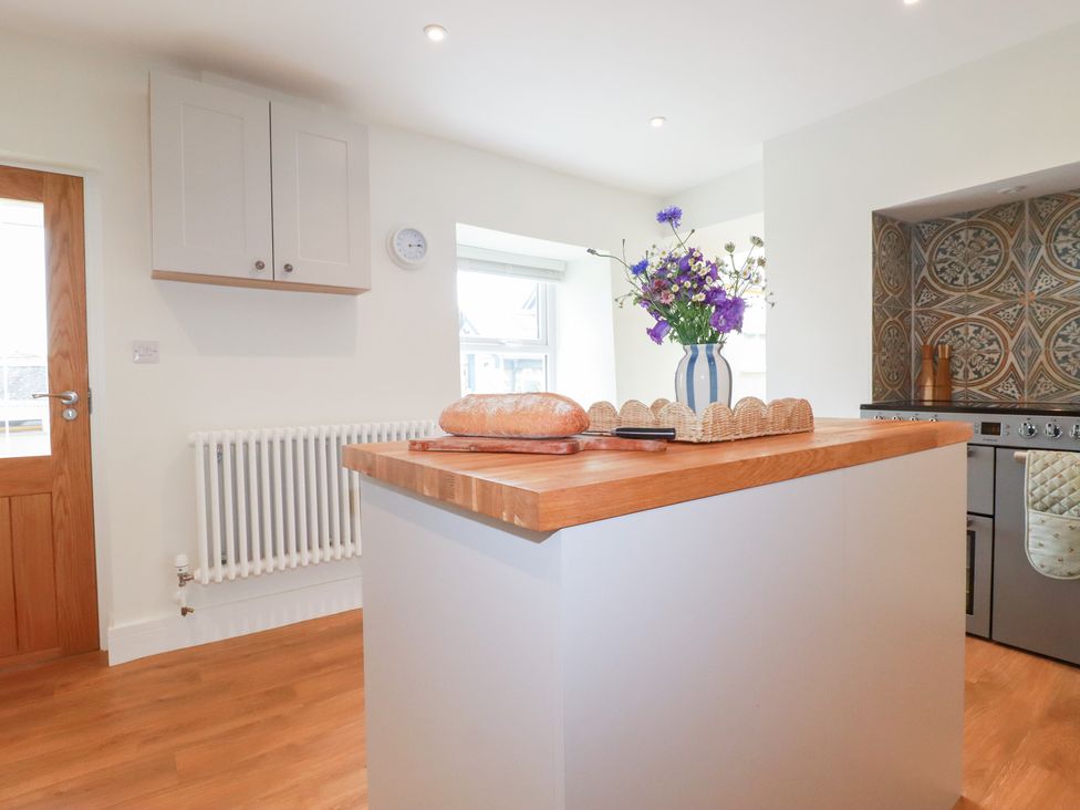 A kitchen with a wooden island and flowers at Glendale in Port Isaac