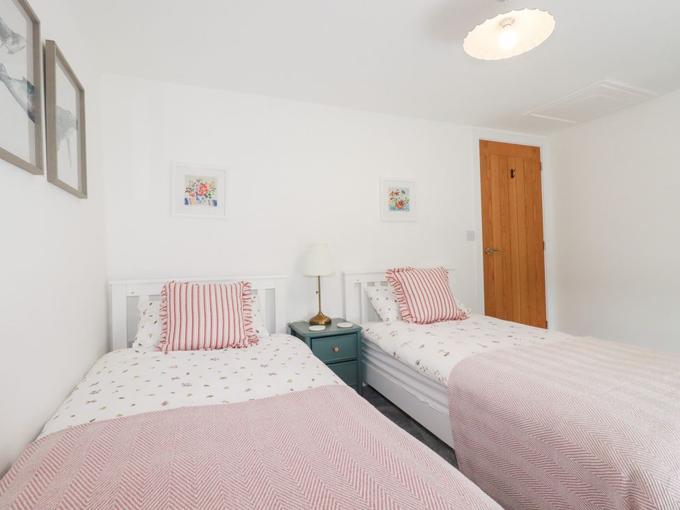 A bedroom with two beds and a bedside table at Glendale in Port Isaac