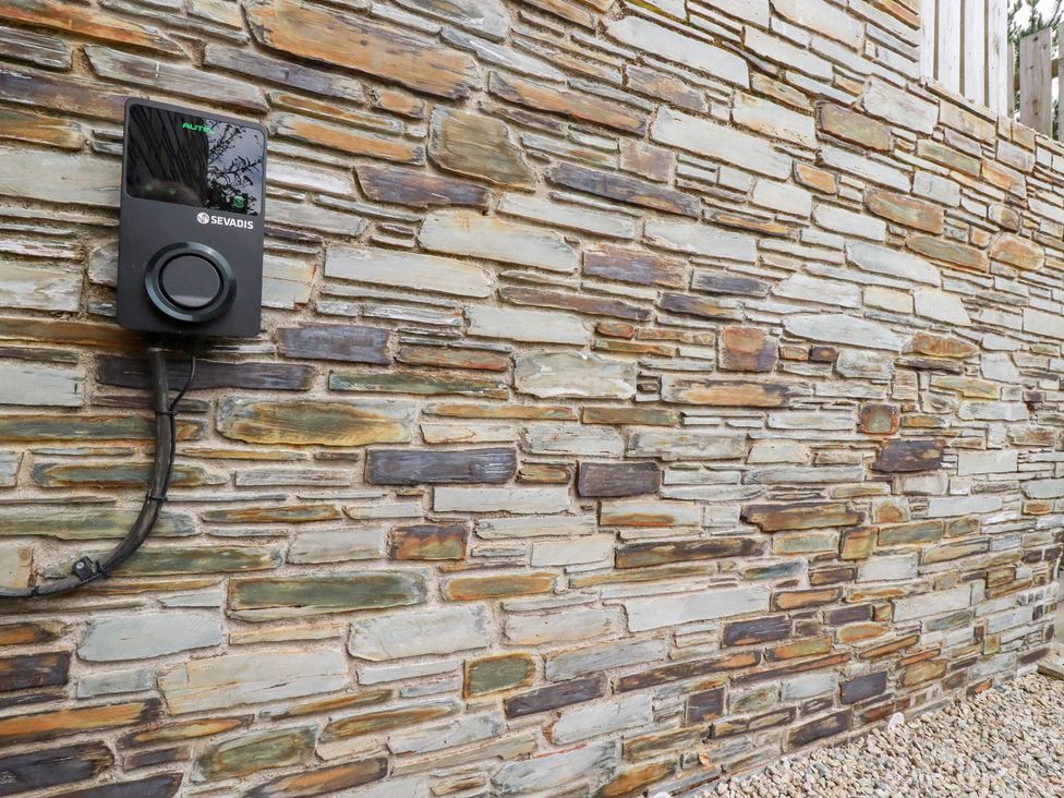 A wall-mounted electric vehicle charger on a stone wall at Glendale in Port Isaac