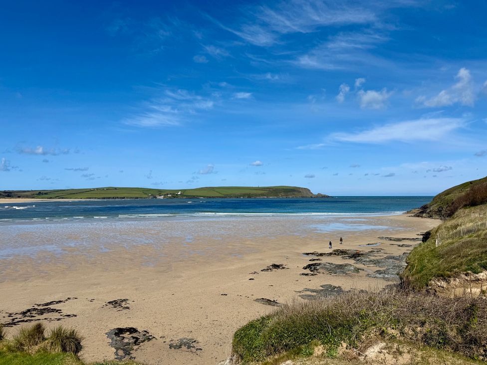 A beach with two people walking along the shore at Glendale in Trelights near Port Isaac