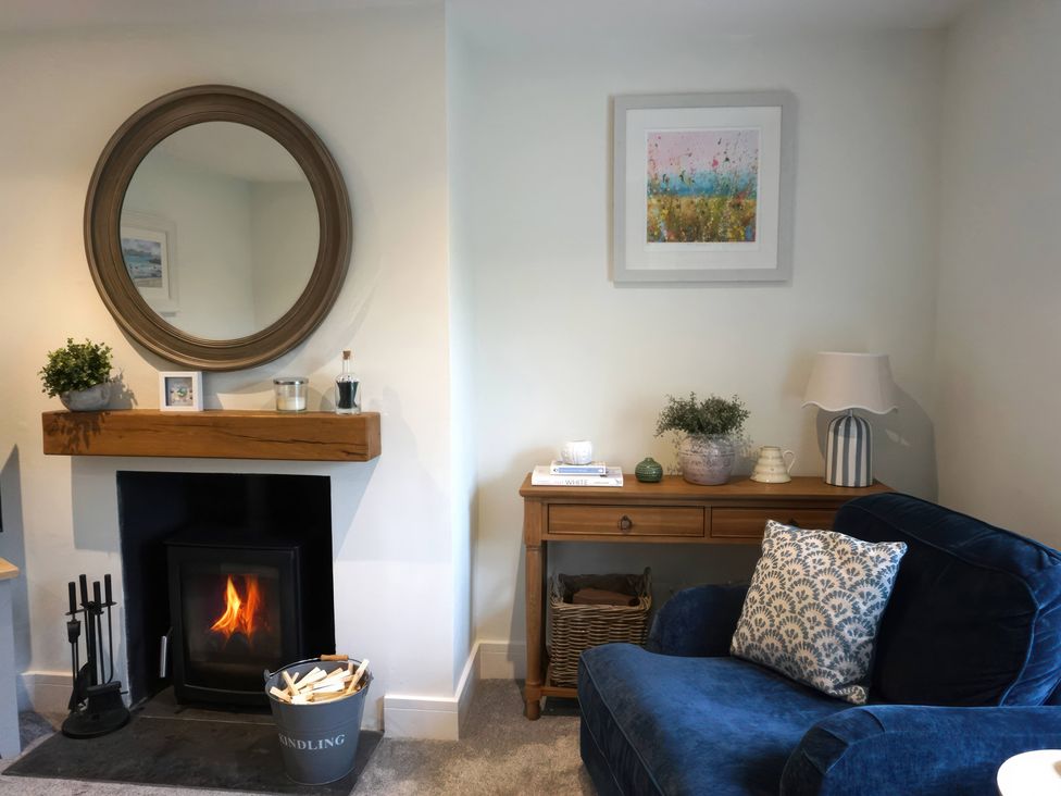 A living room with a fireplace and a blue armchair at Glendale in Trelights near Port Isaac