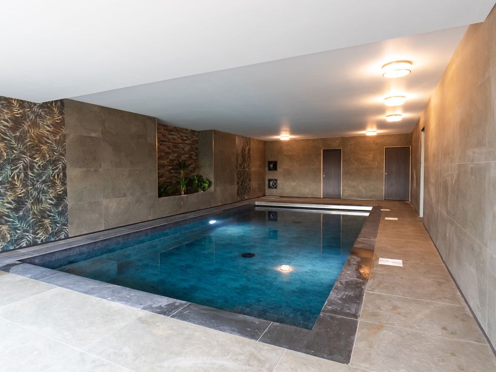An indoor pool area with tile flooring and decorative walls at 30 High Lane East Ilkeston
