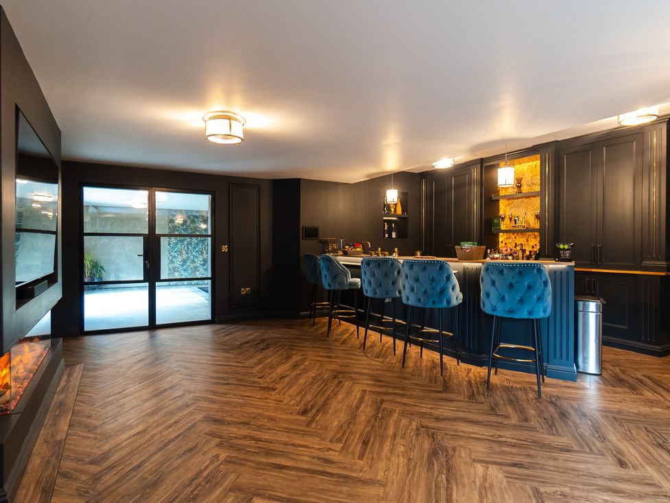 A kitchen with a bar and barstools at 30 High Lane East Ilkeston