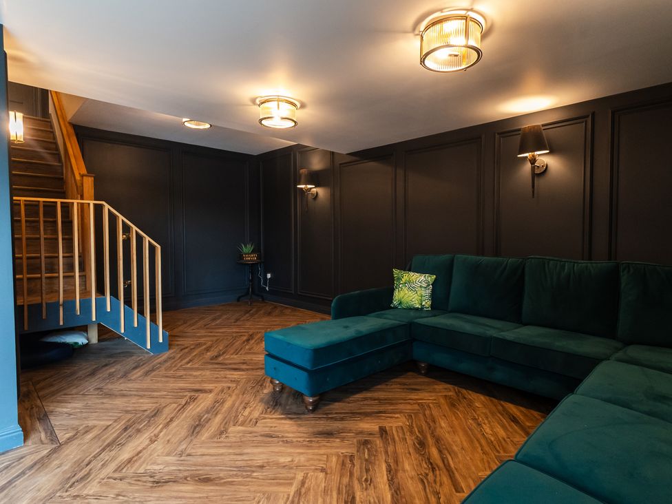 A snug with a green sofa and staircase at 30 High Lane East Ilkeston