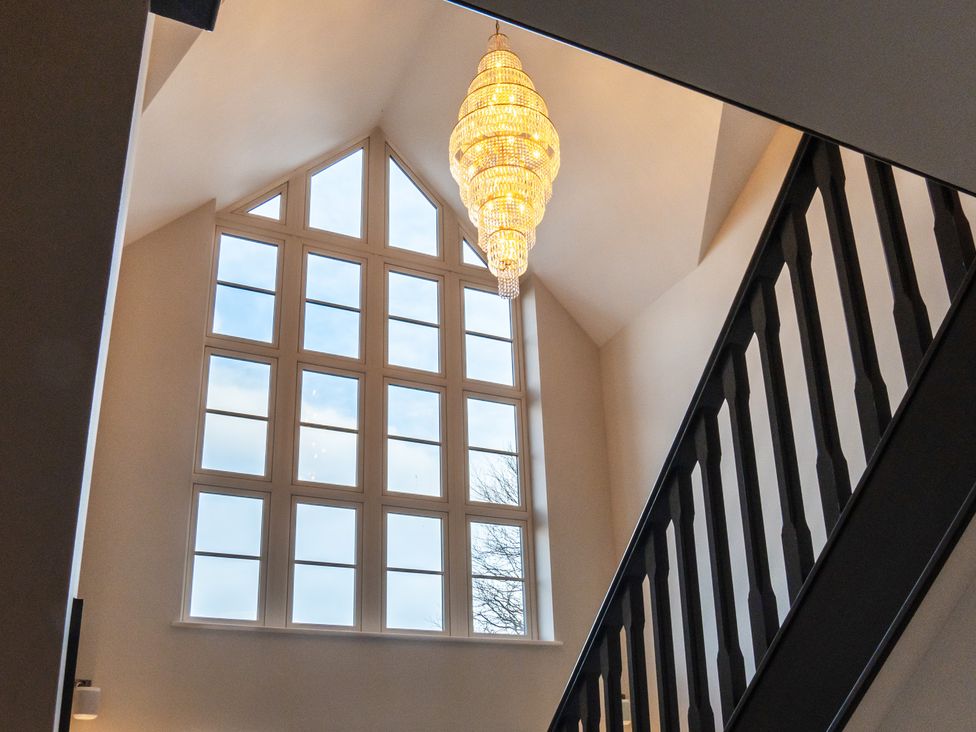 A hallway with a chandelier and large windows at 30 High Lane East Ilkeston