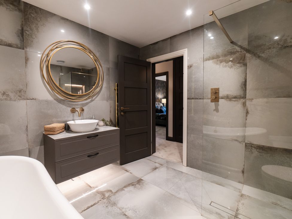 A bathroom with a bathtub, sink, and shower at 30 High Lane East Ilkeston