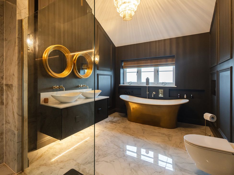 A bathroom with a bathtub, toilet, and washbasins at 30 High Lane East Ilkeston