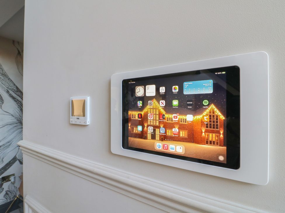 A tablet mounted on the wall next to a thermostat at Hallam Retreat in West Hallam
