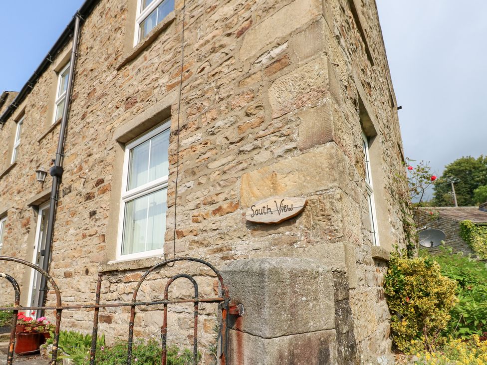 A stone wall with a window and nameplate at South View, Gunnerside