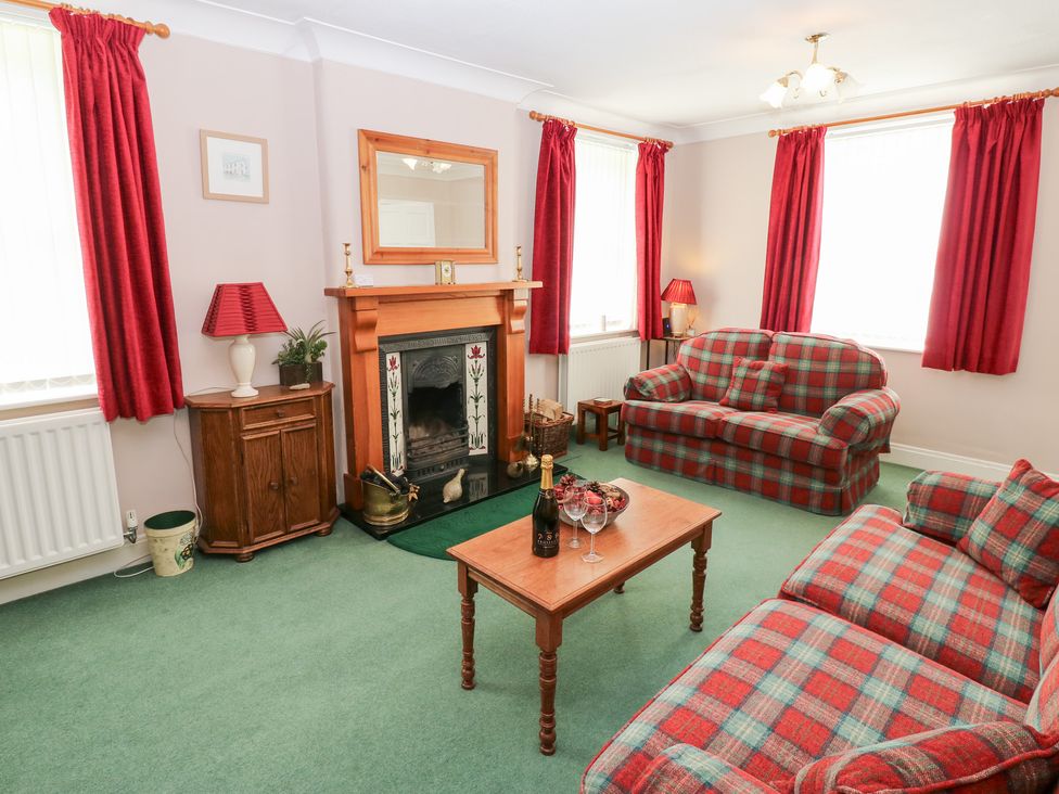 A living room with a fireplace and seating area at South View, Gunnerside near Reeth