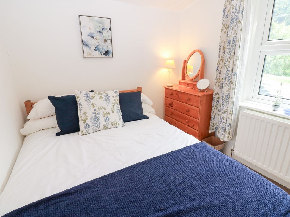 A bedroom with a bed, dresser and window at South View, Gunnerside