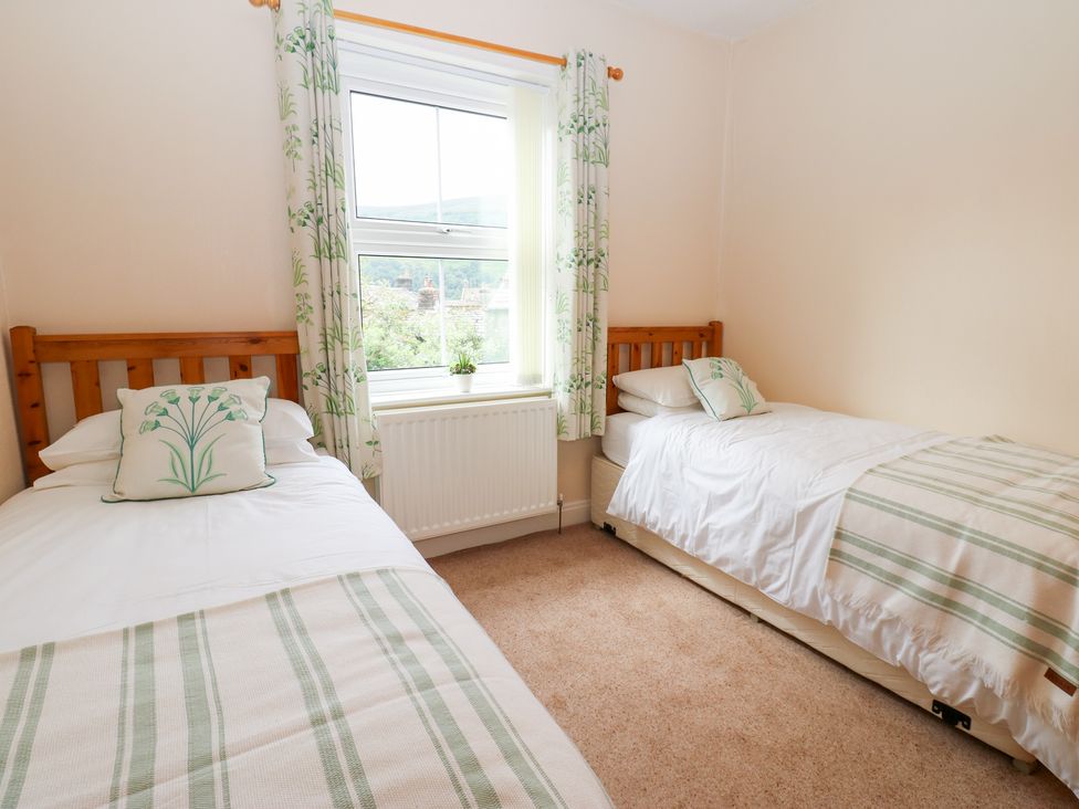 A bedroom with two single beds and a window at South View, Gunnerside