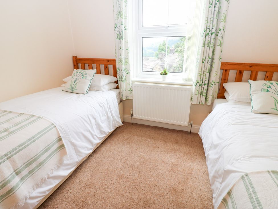 A bedroom with two beds and a window at South View, Gunnerside