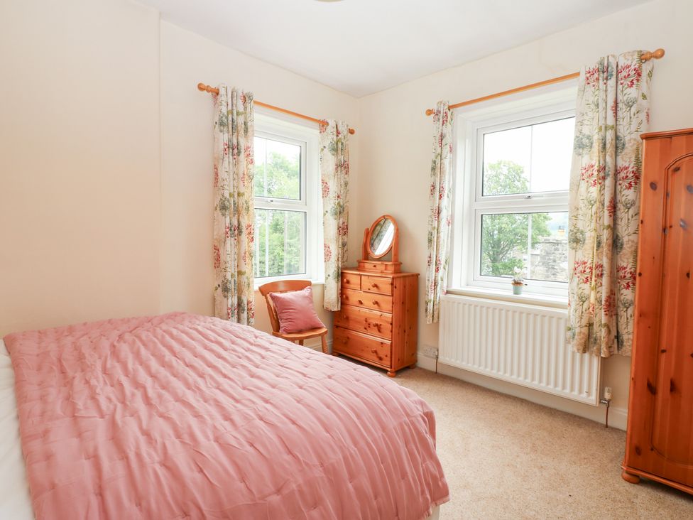 A bedroom with a bed and mirror at South View, Gunnerside