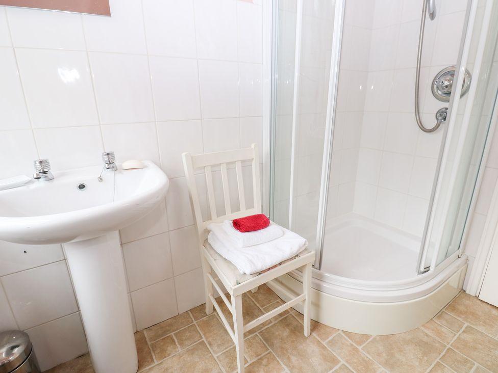 A bathroom with a sink, shower, chair, and towels at South View, Gunnerside