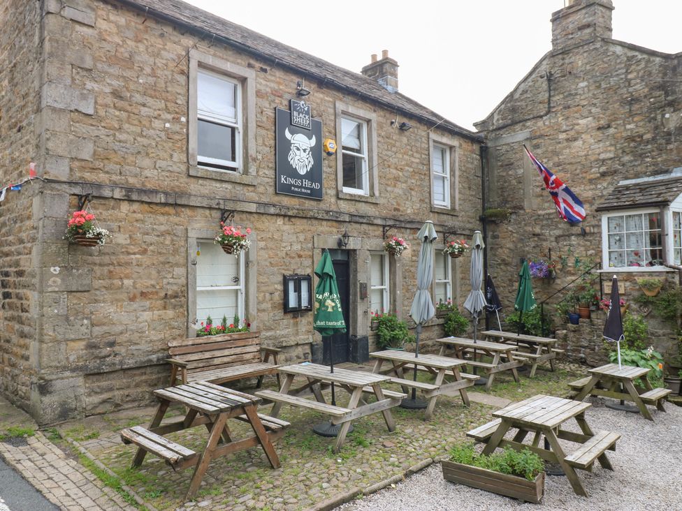 A pub with tables and umbrellas outside at Kings Head, Gunnerside near Reeth