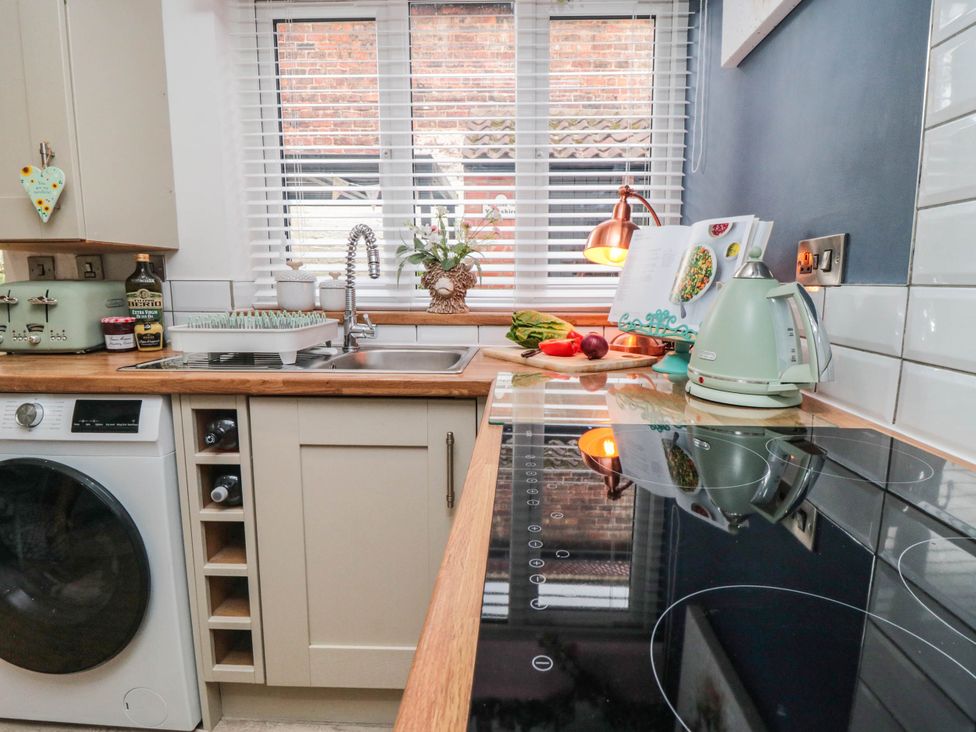 A kitchen with a stove, kettle, and washing machine at 5 South Side