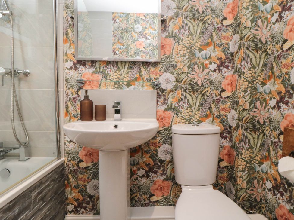 A bathroom featuring a sink, toilet, shower, and mirror at 5 South Side