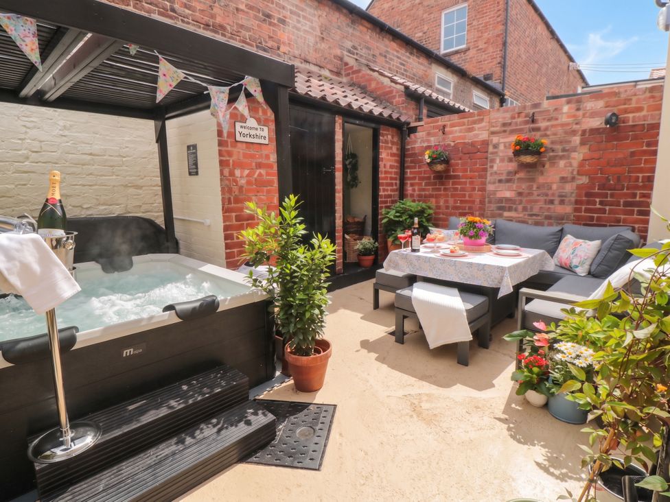An outdoor area with a hot tub, table, and seating at 5 South Side