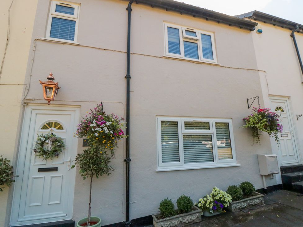 A front view of a house with a door and flower arrangements at Acorn Cottage in Hutton Rudby