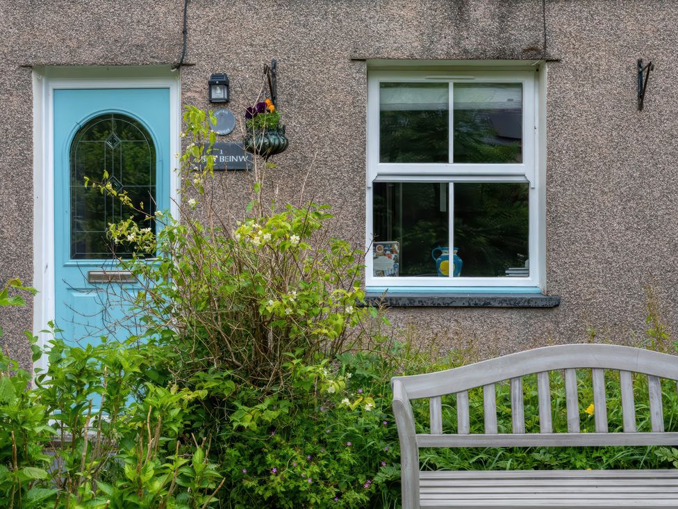 A door and window with plants and a bench at 1 Aberbeinw in Dolwyddelan