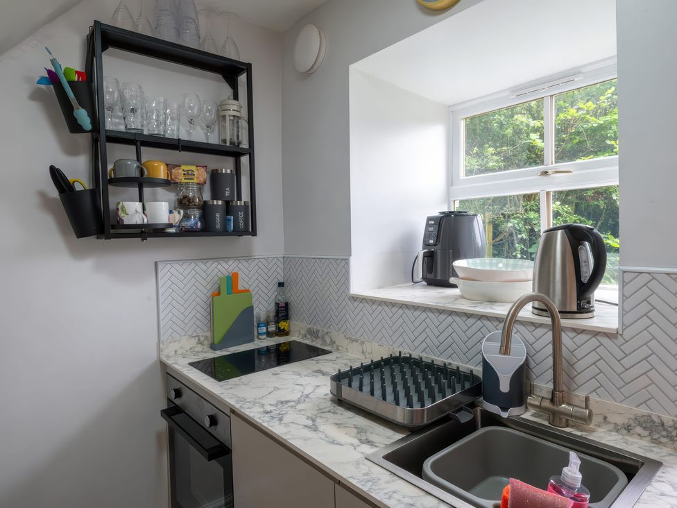 A kitchen with a sink, stove, and shelf at 1 Aberbeinw, Dolwyddelan