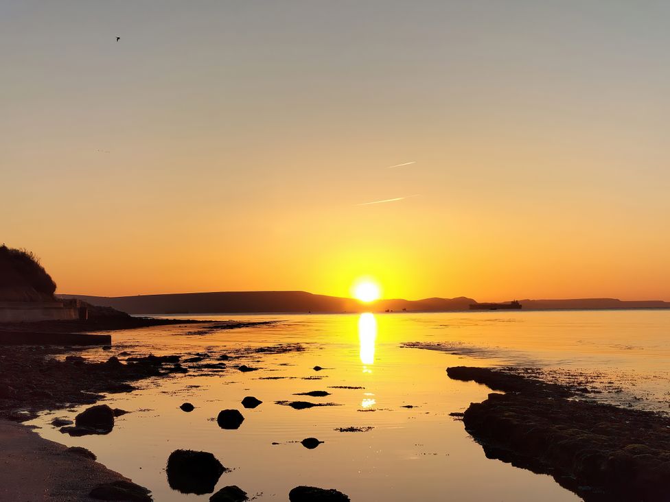 A sunset over water with rocks at The View in Weymouth
