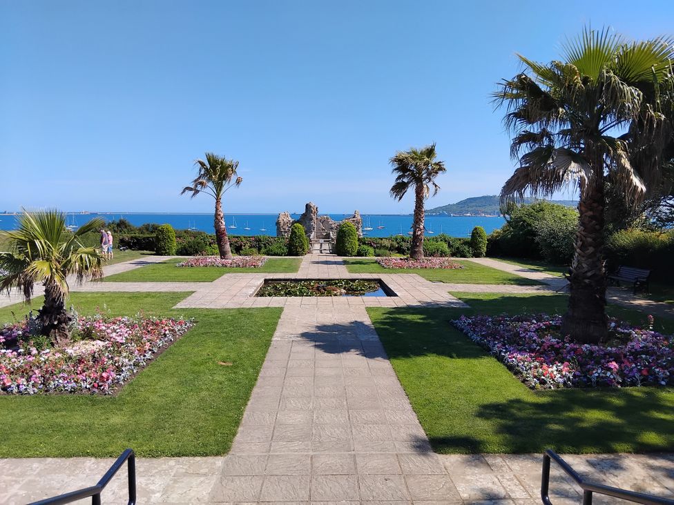 A garden with palm trees and flowers leading to the sea at The View in Weymouth