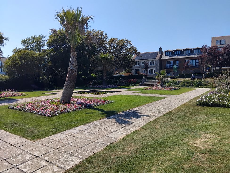 A garden with flower beds and palm trees at The View in Weymouth
