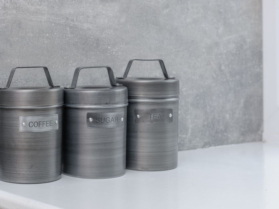 Three metal canisters labeled coffee, sugar, and tea in a kitchen at The Forge in Morpeth