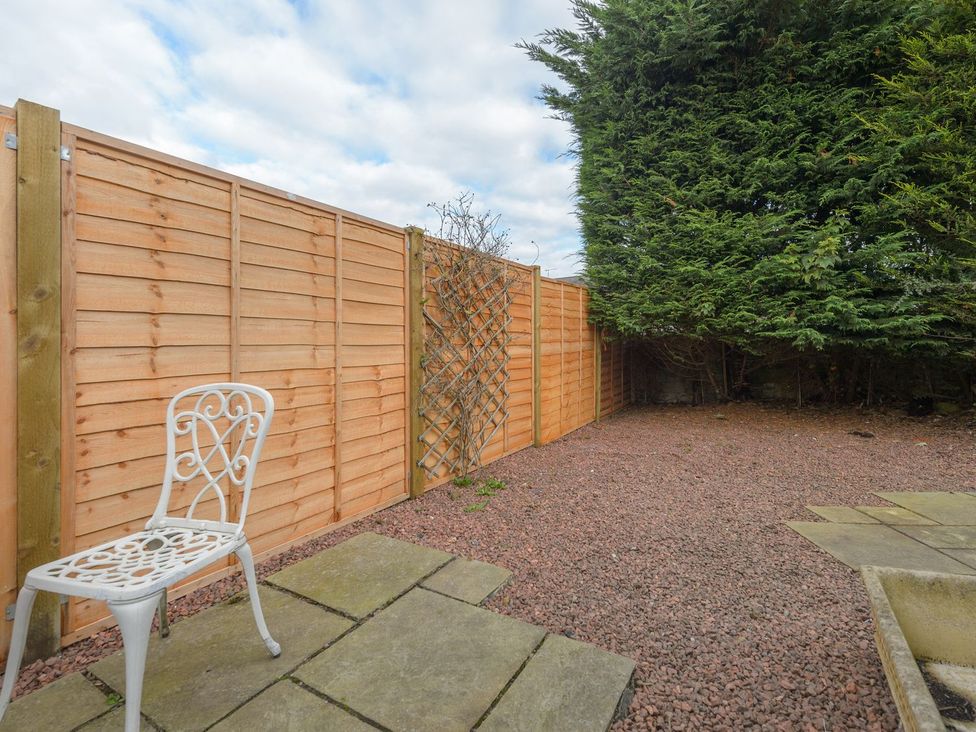 A garden with gravel, a chair, and a fence at The Forge in Morpeth