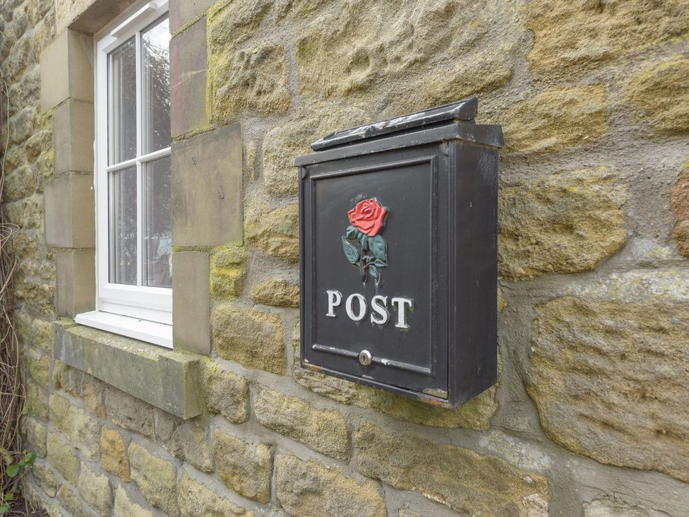 A mailbox mounted on a stone wall next to a window at The Forge in Morpeth