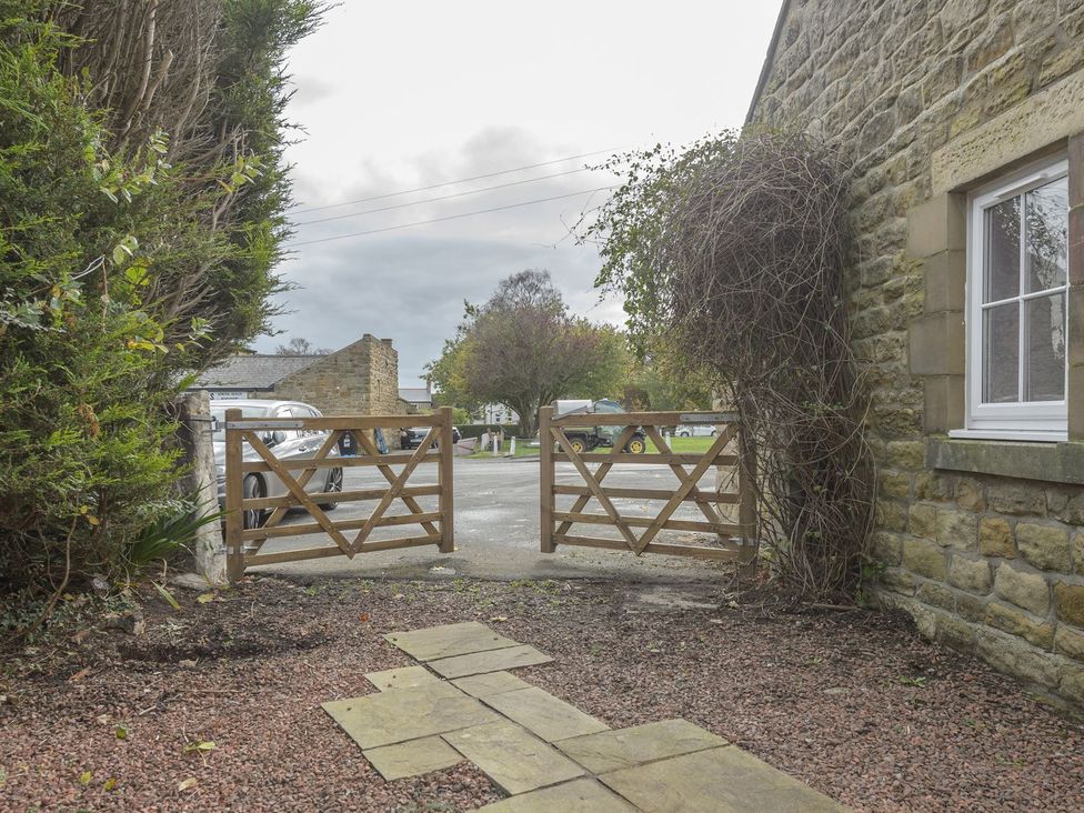 An outdoor area with a wooden gate leading to a parking area at The Forge in Morpeth