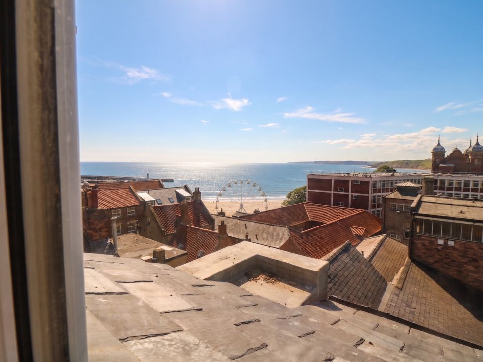 A view of the sea and buildings with a ferris wheel at The Newborough Apartment 5 Scarborough