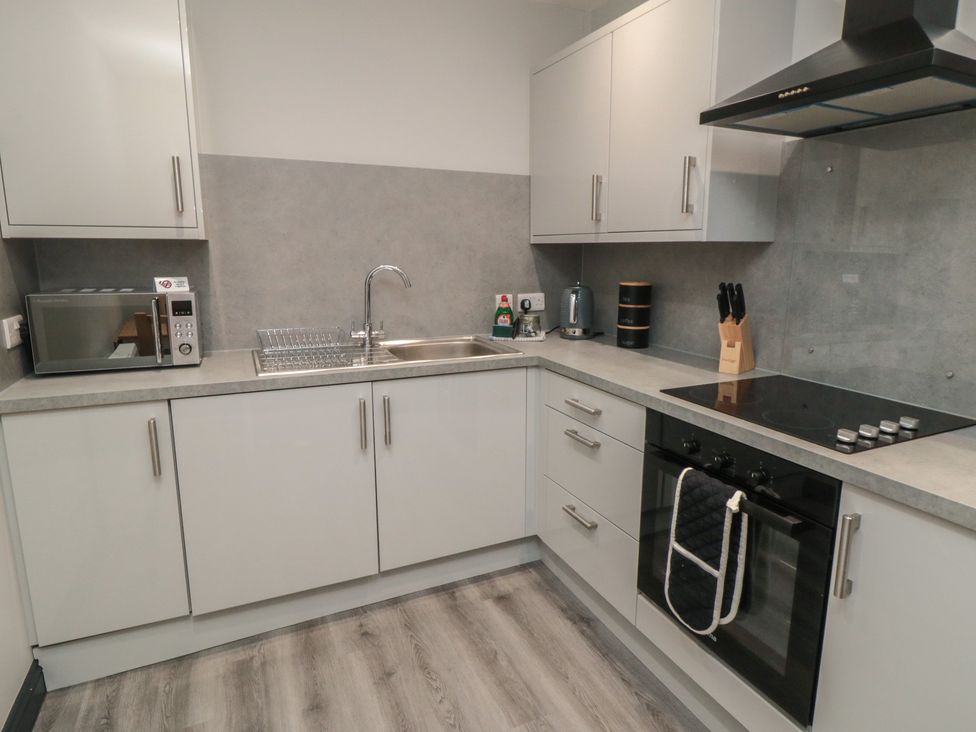 A kitchen with modern appliances and fixtures at The Newborough Apartment 1 Scarborough