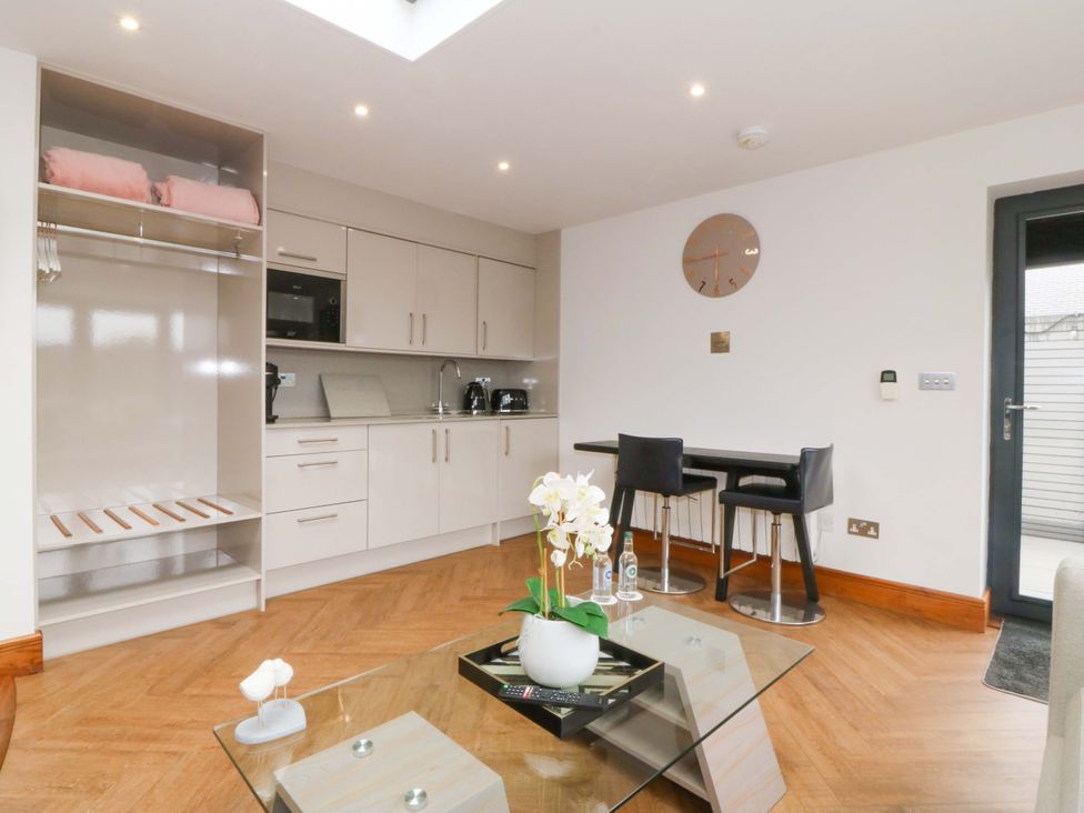 A kitchen with cabinets and bar stools at Lodge in Llangefni